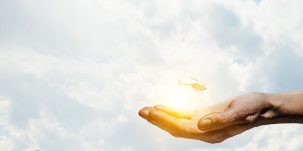 Photo hands holding clouds with flying helicopter. mixed media