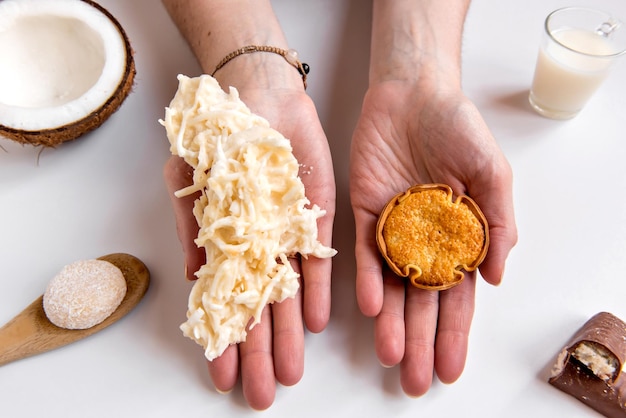 Hands holding Coconut and coconut candy cocada on white background