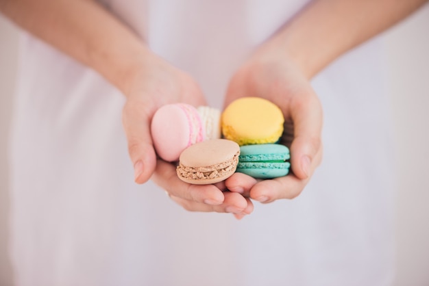 Руки, держащие красочные пастельные пирожные macarons или macaroons