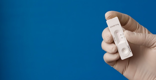 Hands holding coronavirus test on blue background