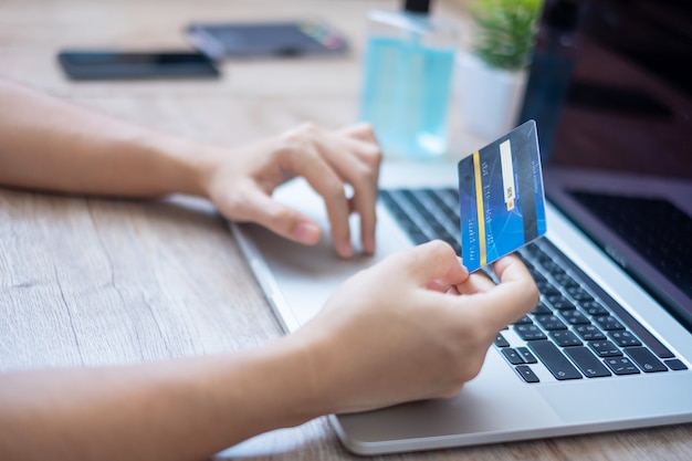 Hands holding credit card and using laptop