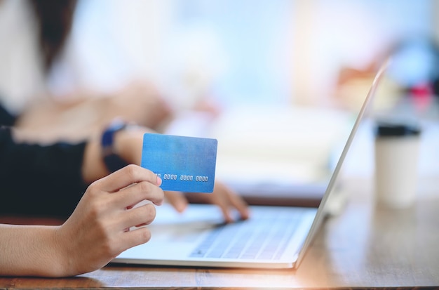 Hands holding credit card and using laptop.