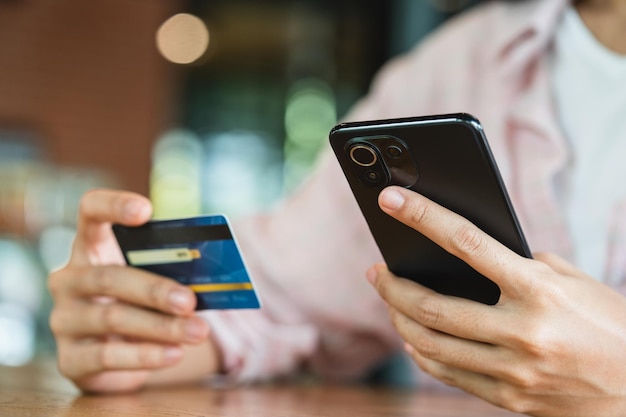 Mani in possesso di carta di credito tramite smartphone concetto di shopping e pagamento online