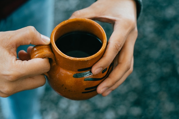 Mani che tengono una tazza di cafã© de olla, tradizionale dal messico.