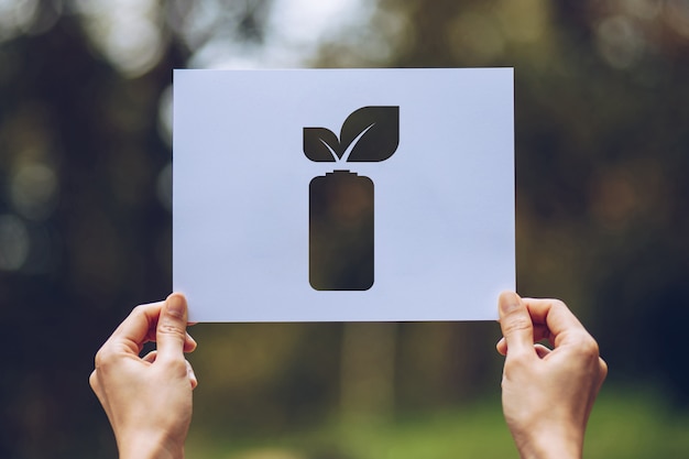 hands holding cut out paper leaves battery saving energy showing