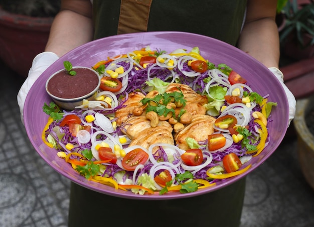 Hands holding dish with pan fried chicken and vegetables