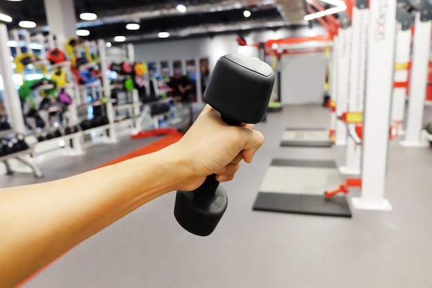 Hands holding dumbbells in sport club or gym and fitness room.