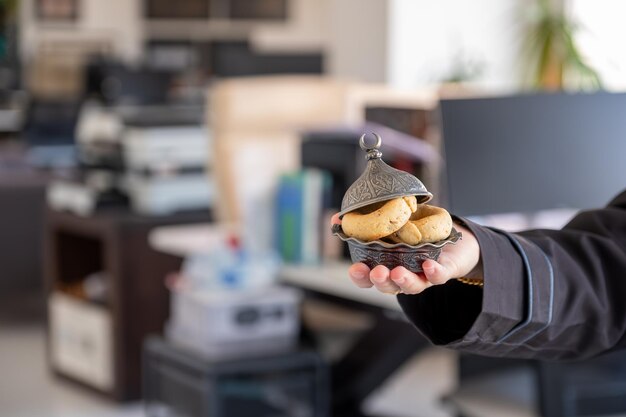 Le mani che tengono i dolci dell'eid in ufficio