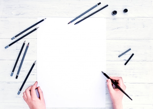 Hands holding the empty white paper sheet, and a calligraphy pen