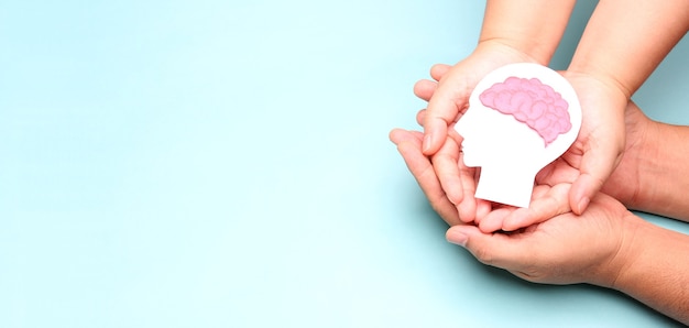 Photo hands holding encephalography brain paper cutout.