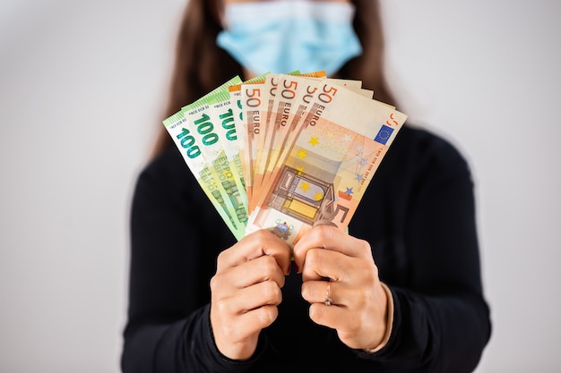Руки держат наличные евро во время пандемии коронавируса
