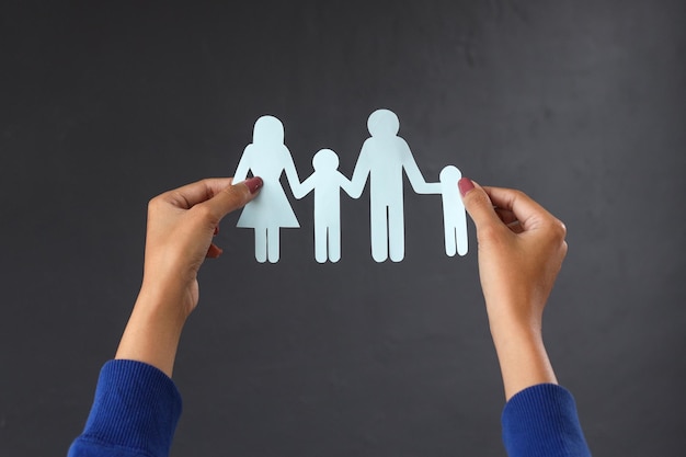 Hands holding family paper cutout. Insurance and medical care concept.