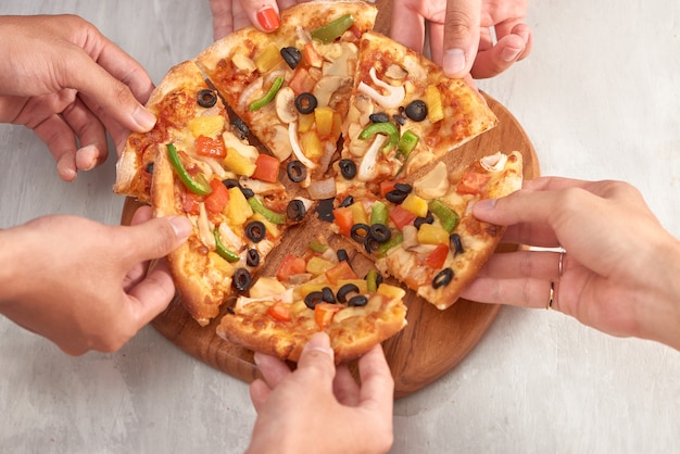 Photo hands holding fresh baked pizza with melting cheese