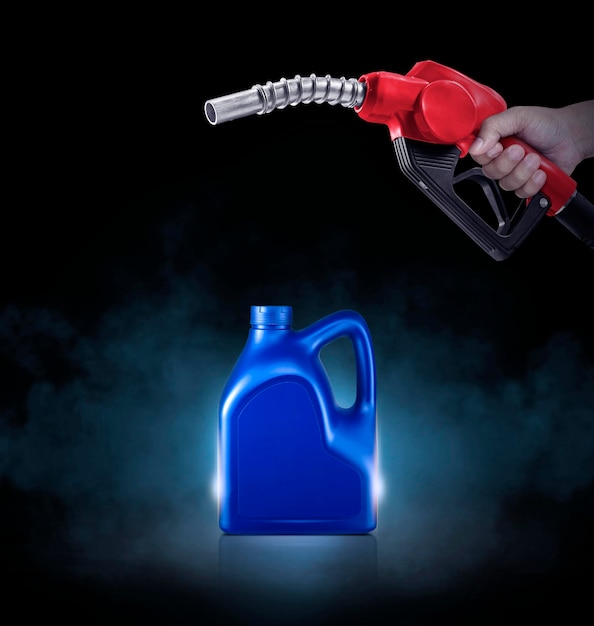 Hands holding Fuel nozzle and blue bottle of engine oil on black background with smoke