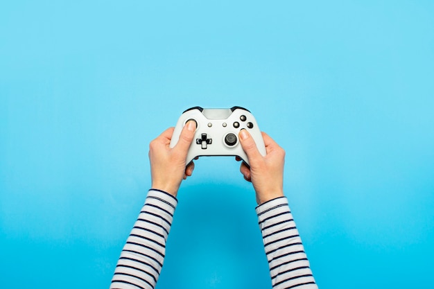 Photo hands holding a gamepad on a blue space. banner. concept games, video games