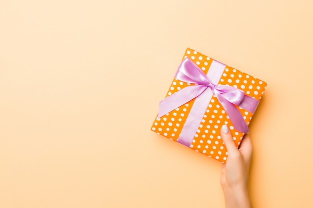 hands holding gift box with dotted wrapping paper and ribbon