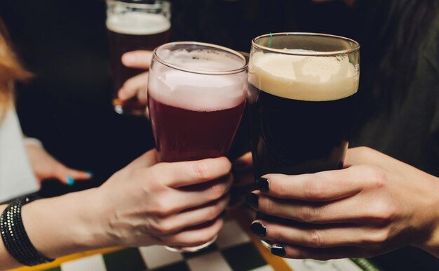 Foto mani che tengono bicchieri di birra al pub un gruppo di amici si sta godendo la birra in città da vicino sui bicchieri