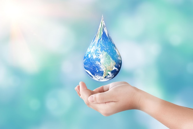 Photo hands holding global in drop shape on blurred nature background world day for water and sustain for earth concept elements of this image furnished by nasa