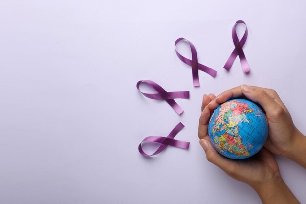 Photo hands holding a globe purple violet ribbons in a row for world cancer day concept