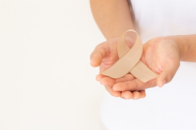 Photo hands holding gold ribbon on white background for childhood cancer.