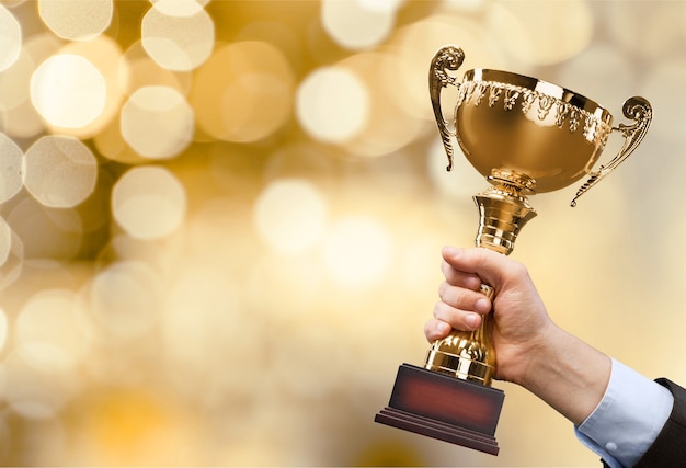 Hands holding golden trophy on background