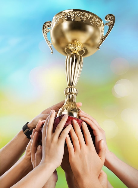 Photo hands holding golden trophy on light background