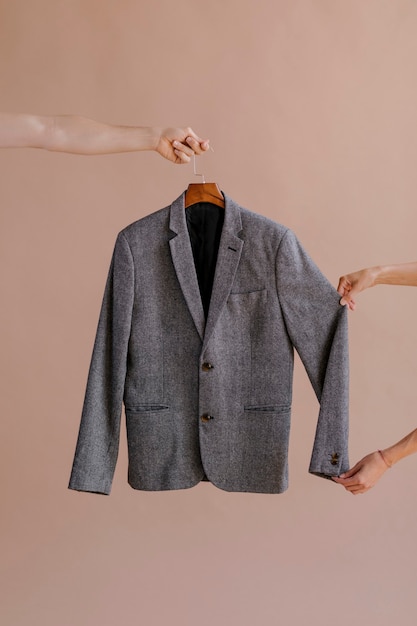 Hands holding a gray blazer in a hanger