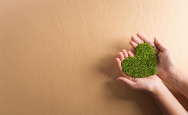 Hands holding green heart on brown background World environment day earth day and save earth concept