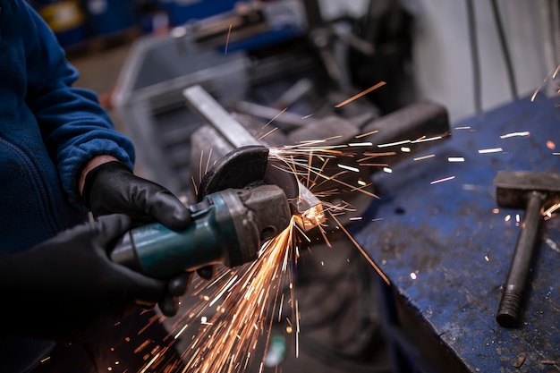 Hands holding a grinder to cut stainless steel pipe