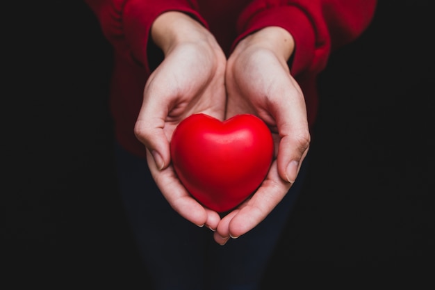 Photo hands holding a heart on a dark background