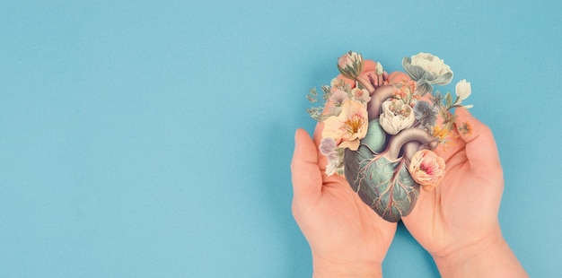 Hands holding human heart with flowers, love and emotion concept, good hearted person, help