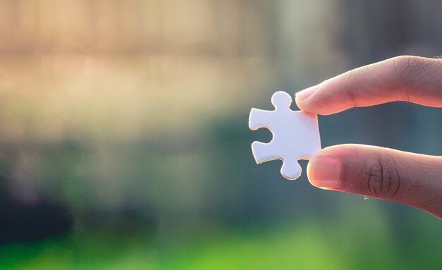 Hands holding a jigsaw puzzle with blur background detail object