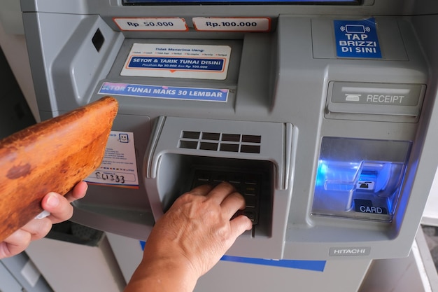 Hands holding leather wallet withdrawing some cash from ATM in Yogyakarta 5 February 2023