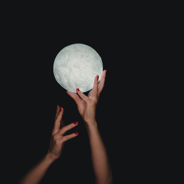 Photo hands holding moon against black background