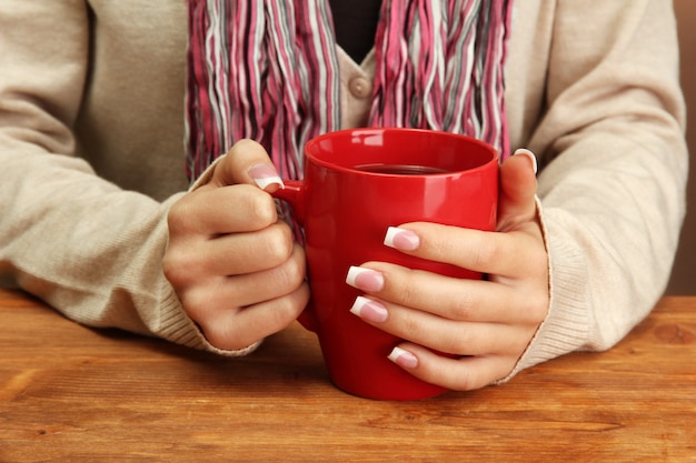 Hands holding mug of hot drink, close-up