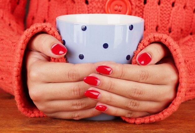 Hands holding mug of hot drink, close-up