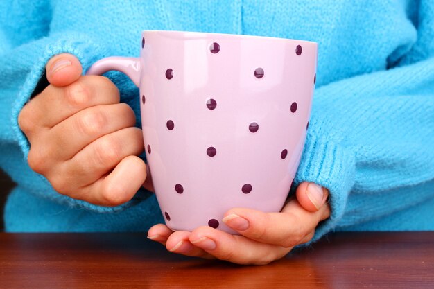 Mani che tengono il primo piano della tazza di bevanda calda