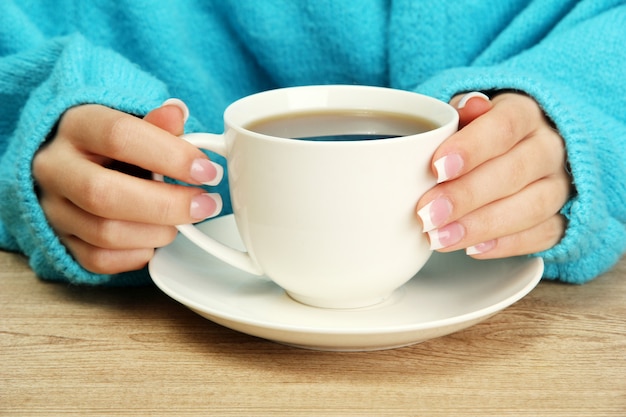 Hands holding mug of hot drink, close-up