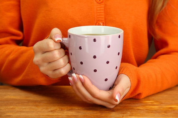 Hands holding mug of hot drink, close-up