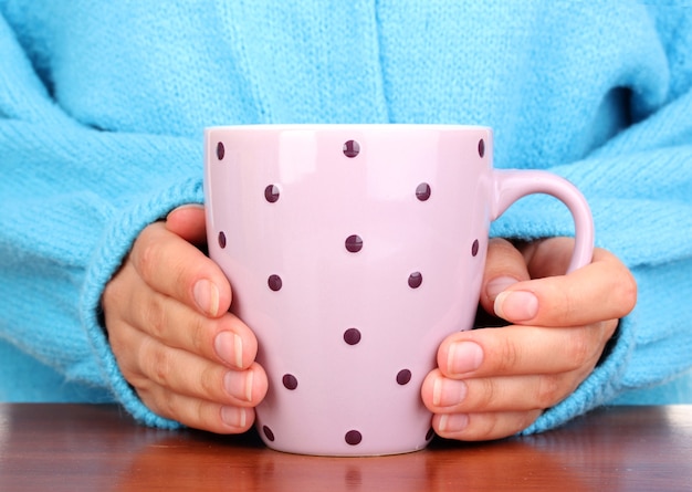 Mani che tengono tazza di bevanda calda, primo piano