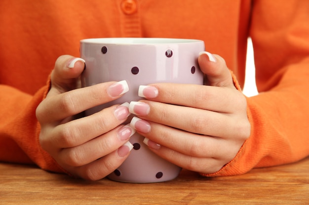 Hands holding mug of hot drink, close-up