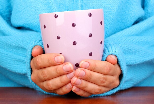 Hands holding mug of hot drink close-up