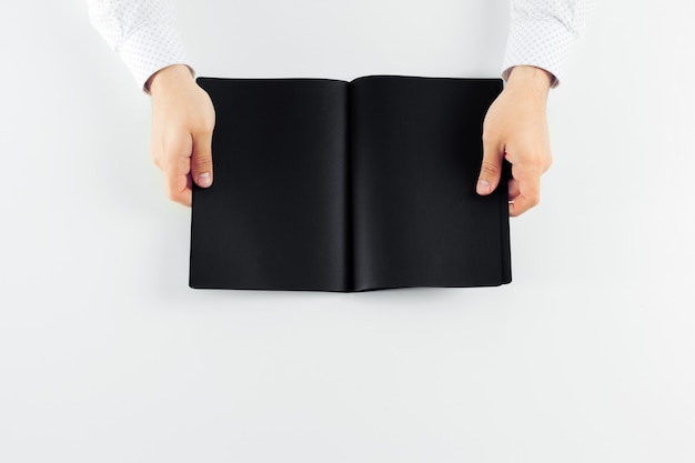 Hands holding a open blank book with black pages