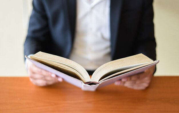 Hands holding an open book on a table