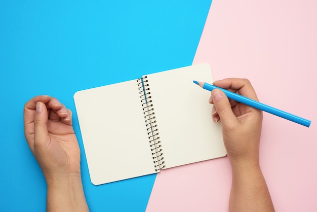 Hands holding open notebook with empty white sheets