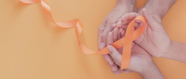 Photo hands holding orange ribbons