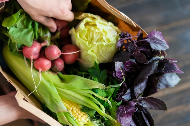 Hands holding package with healthy raw fresh food on dark wooden surface