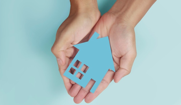 Hands holding paper house, family home and protecting insurance concept