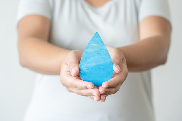 Hands holding a paper water drop element in a concept of water
conservation, save water