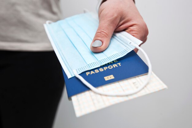 Hands holding a passport with train ticket and the medical mask